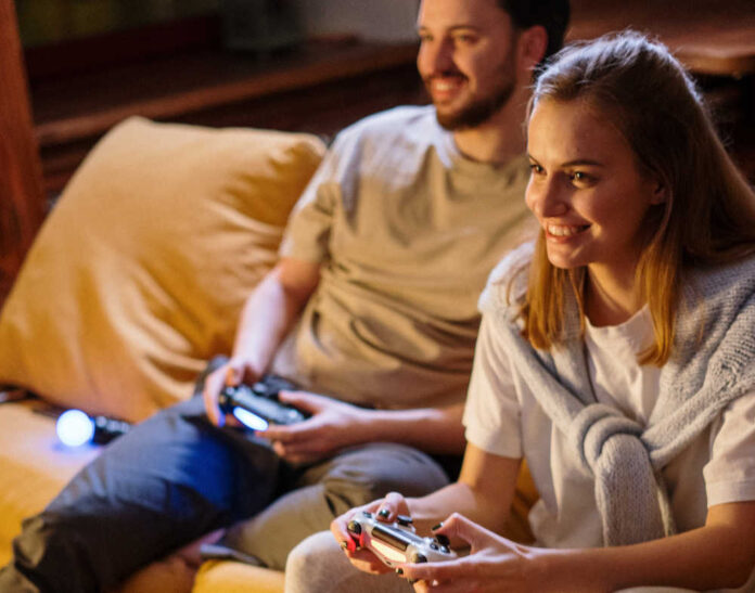 Ett par som spelar tv-spel i soffa. Tv-spel har visat sig öka social kompetens.