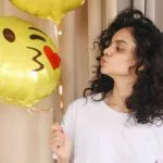 Årets nya emojis 2020. Tjej pussar ballong med emoji.