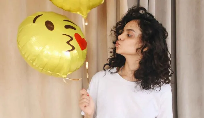 Årets nya emojis 2020. Tjej pussar ballong med emoji.